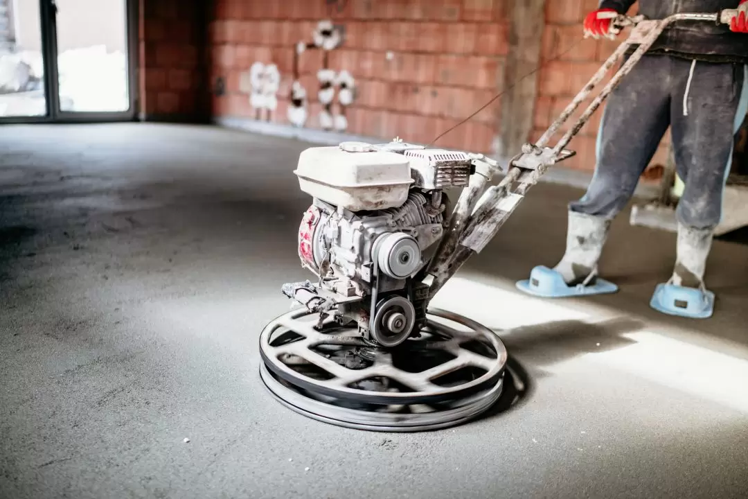 A worker near Spokane Washington using a power trowel inside of a brick building.