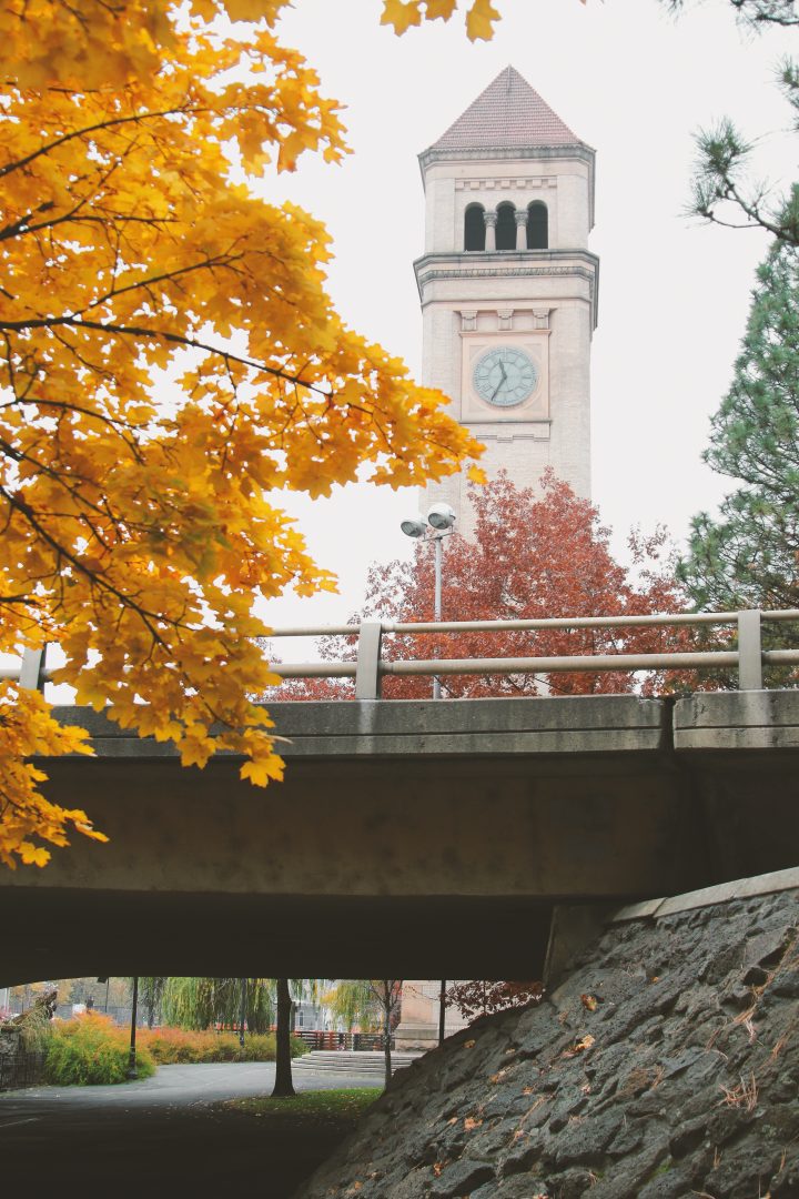 View of the clock tower in Spokane through autumn leaves.